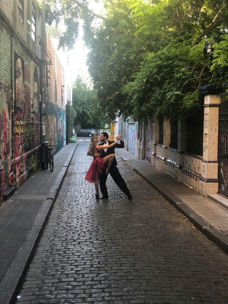 A couple dancing tango on a colorful cobblestone street in Palermo, Buenos Aires.