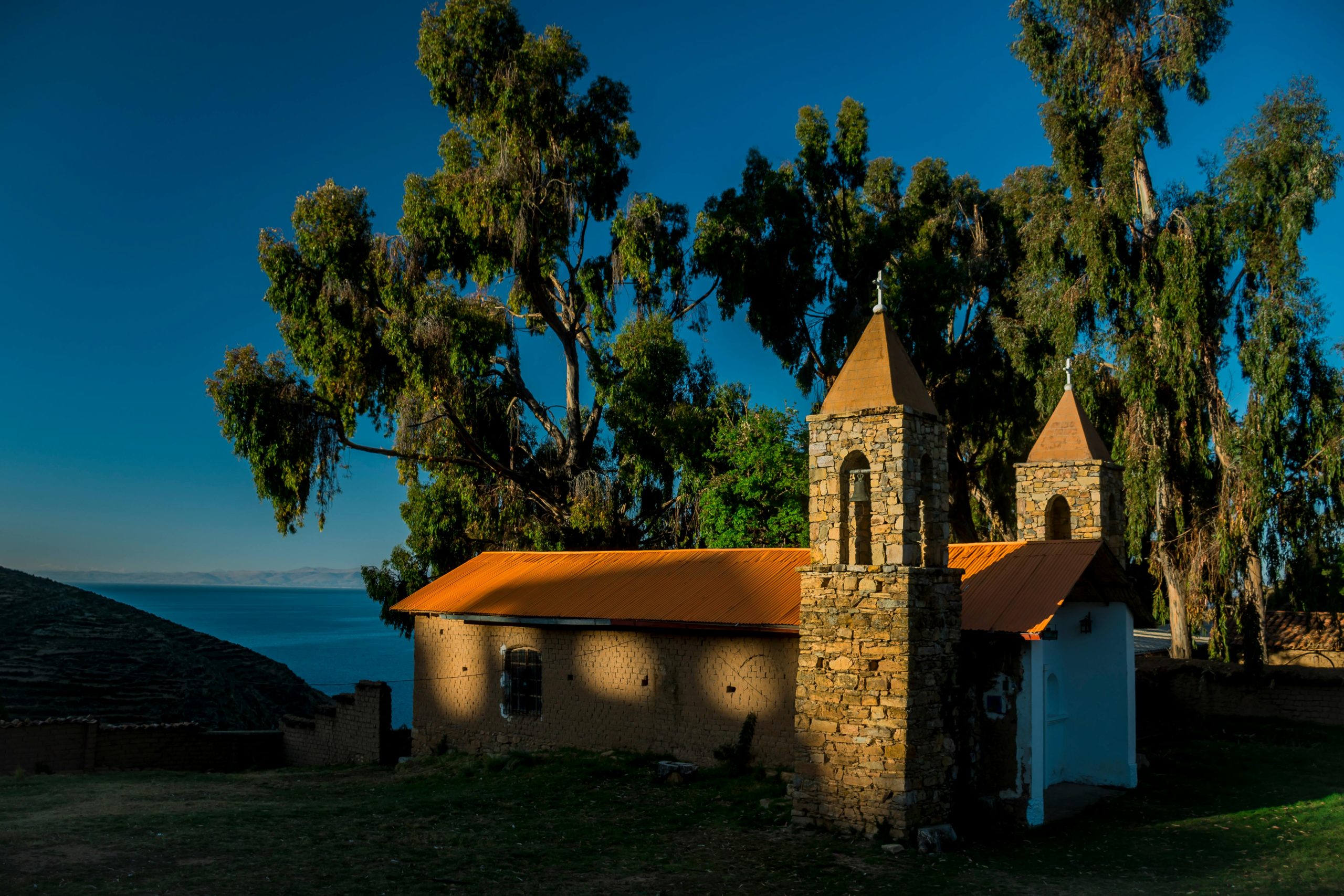 Charming stone chapel surrounded by trees on the shores of Lake Titicaca under the warm sunlight.