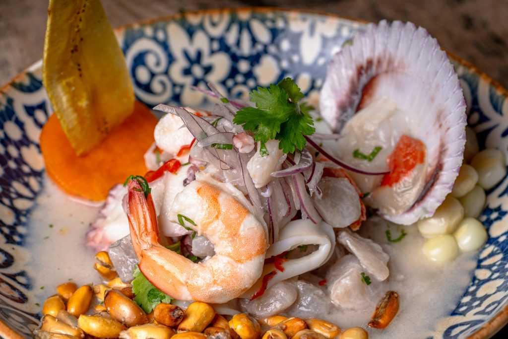 Vibrant mixed seafood ceviche with shrimp, squid, and scallop in a colorful bowl.