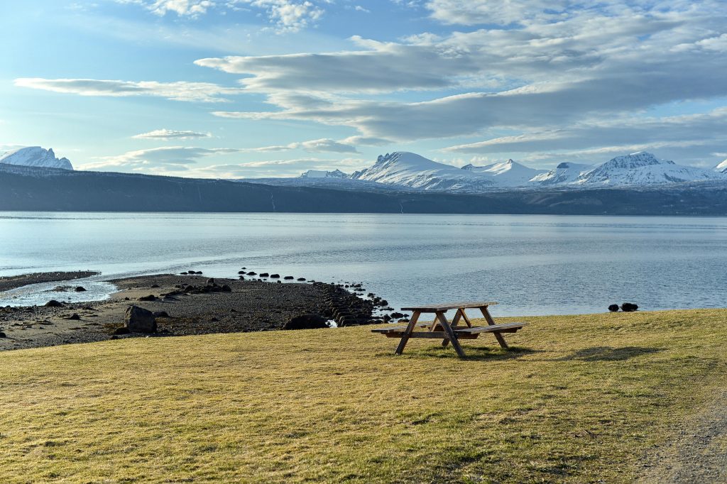 Peaceful fjord landscape with mountains and a picnic table, ideal for outdoor relaxation.