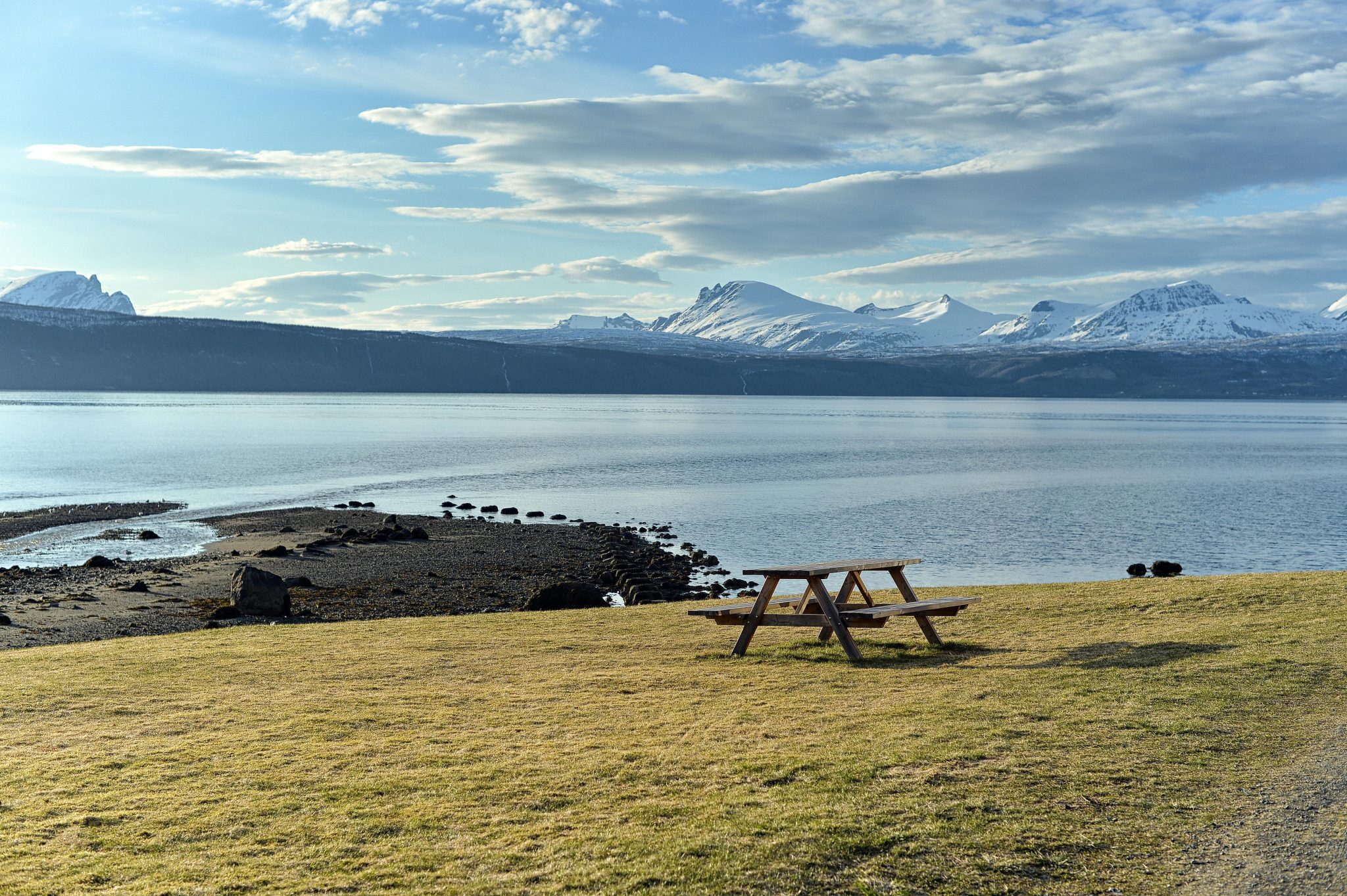 Peaceful fjord landscape with mountains and a picnic table, ideal for outdoor relaxation.