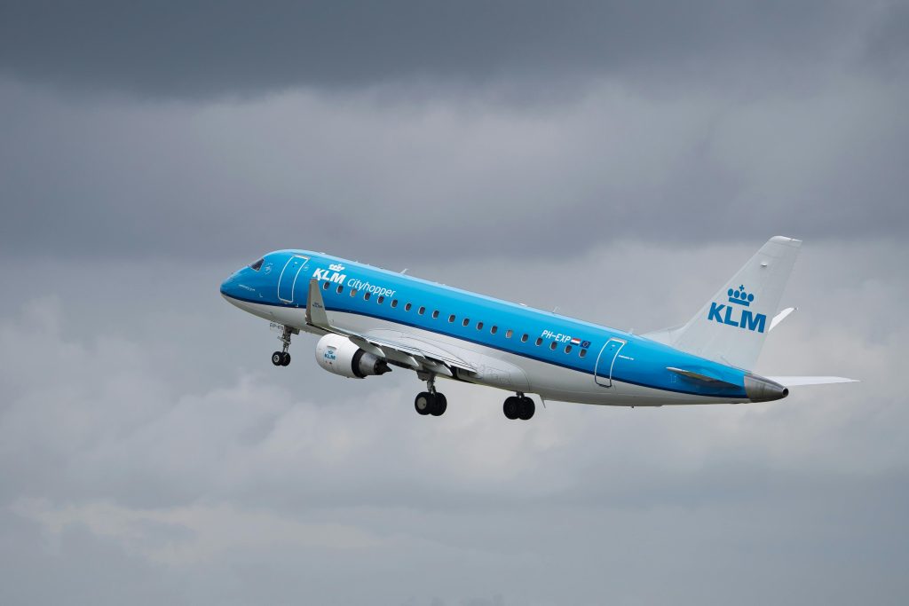 KLM Cityhopper Embraer 190 plane flying against cloudy sky.